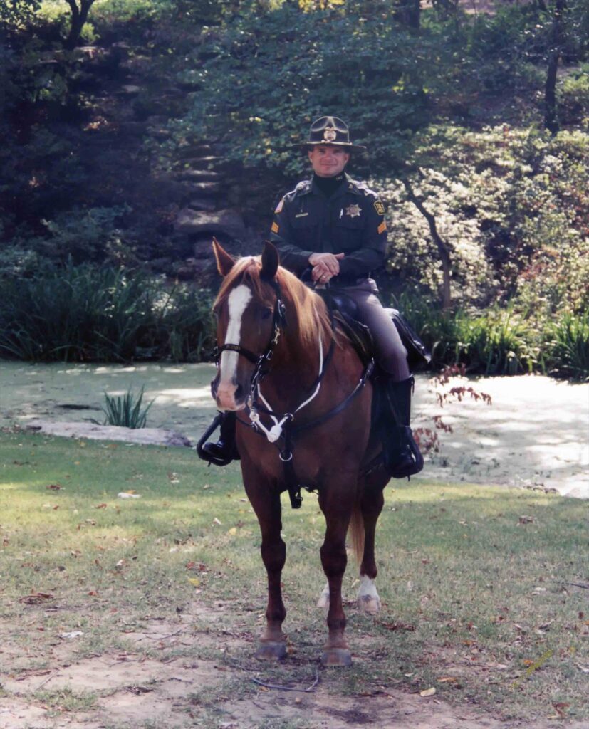 Mounted Tulsa police officer on a chestnut horse in a wooded park