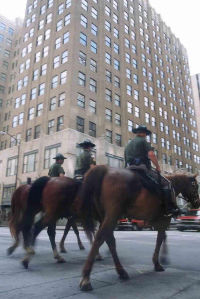 Mounted officers ride past a downtown Tulsa high-rise