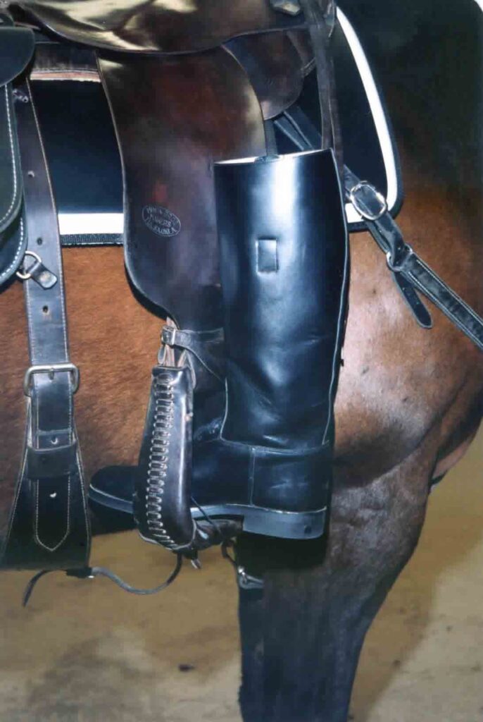 Close-up of a tall black riding boot in the stirrup