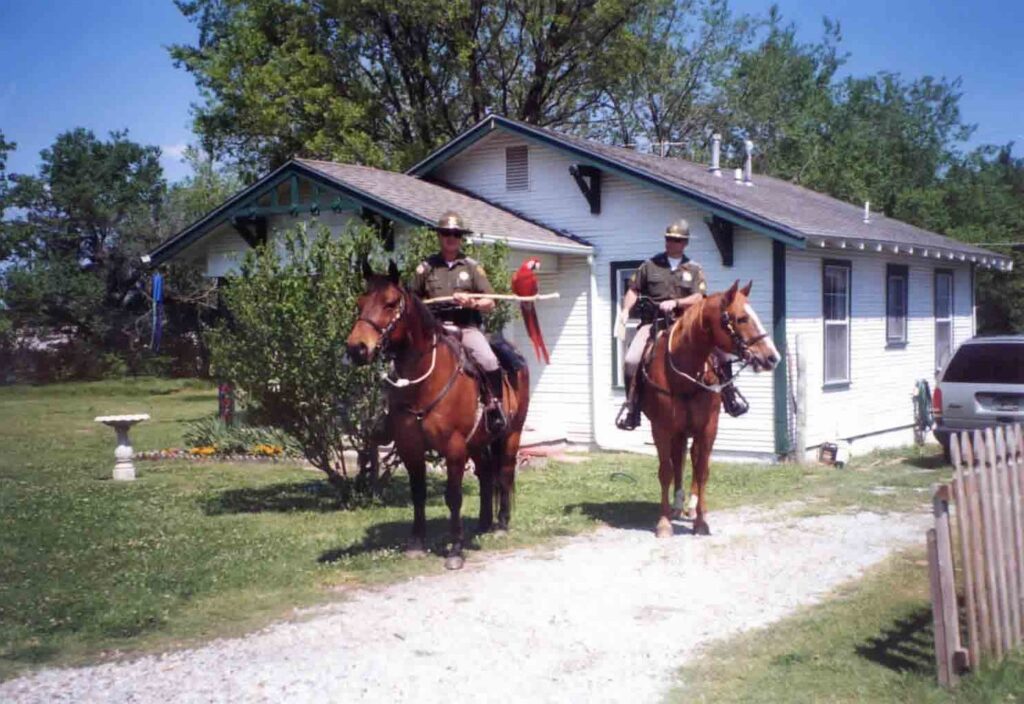 Two mounted officers on horseback outside a white frame house