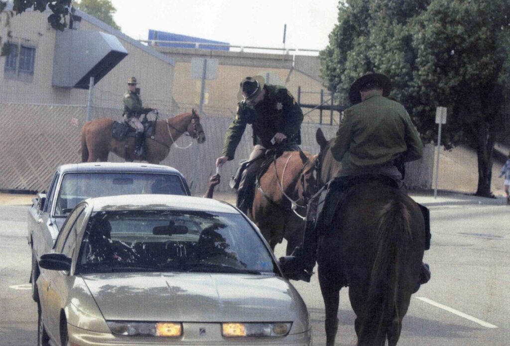 Mounted officers lean down to speak with a driver